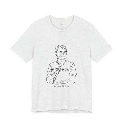 White t-shirt with black line art of Charlie Kirk holding a microphone and text 'Freedom Romans 8:28' on a white background