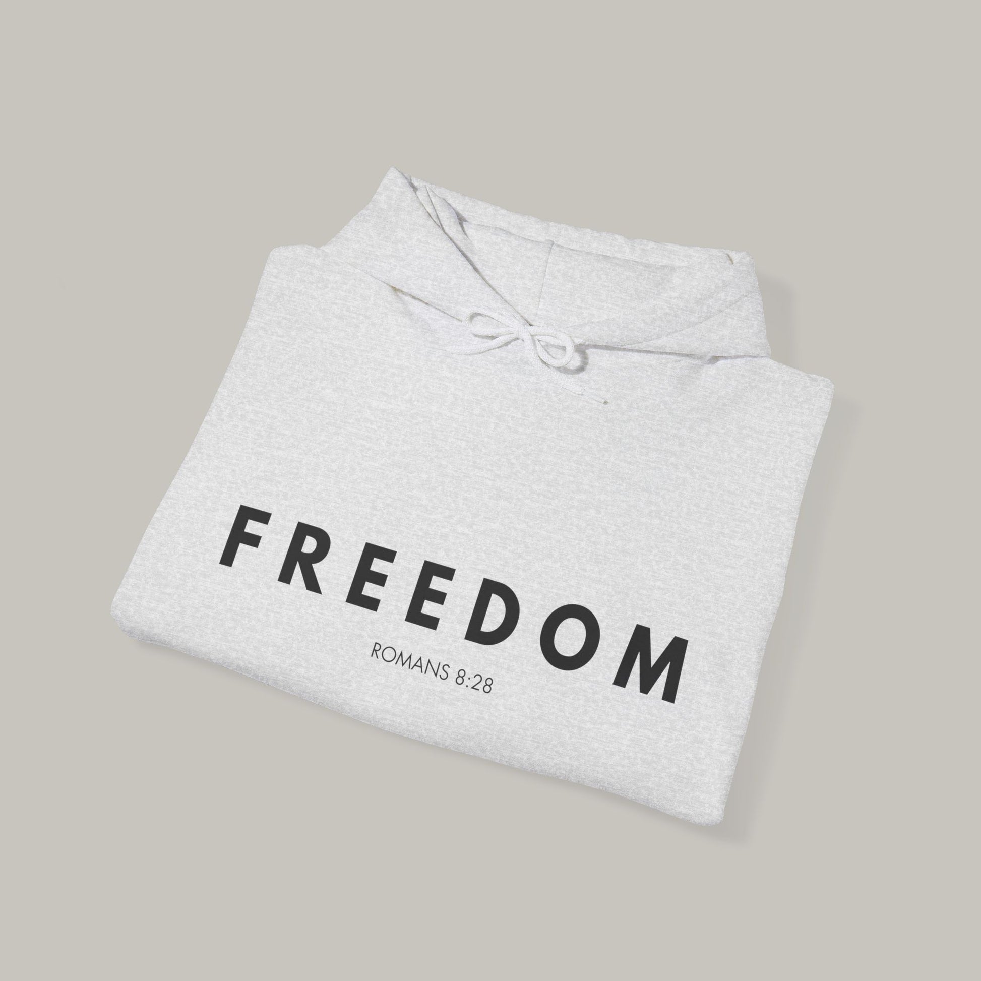Folded gray hoodie with 'FREEDOM' text on a beige background