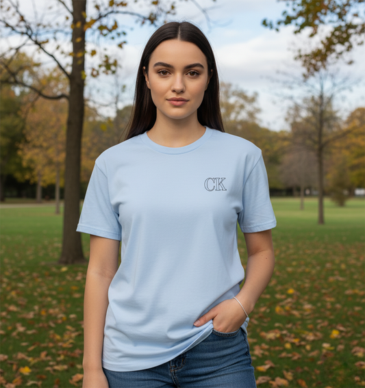 Woman wearing a light blue t-shirt with a logo in an outdoor setting