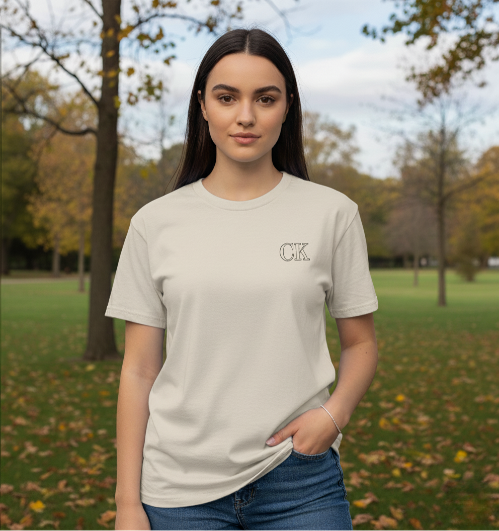Woman wearing a beige t-shirt with a logo in a park setting