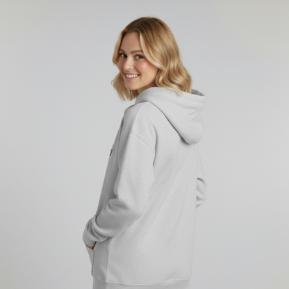 Woman wearing a gray hoodie against a plain background