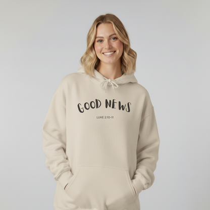 Woman wearing a beige hoodie with 'GOOD NEWS' text on a plain background