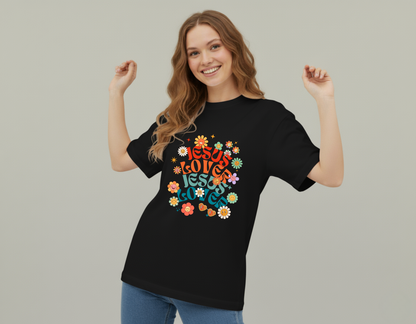 Woman wearing a black t-shirt with colorful text and floral designs on a plain background