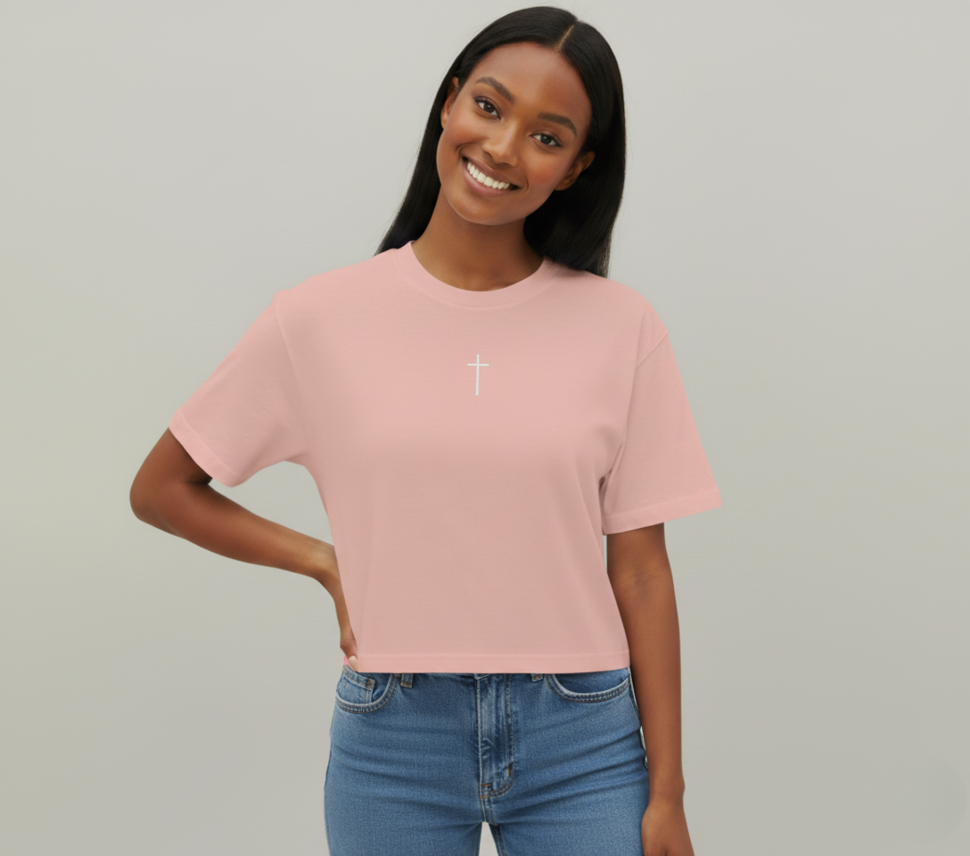 Woman wearing a pink t-shirt with a white cross on a plain background