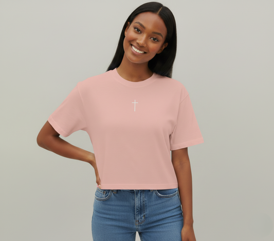 Woman wearing a pink t-shirt with a white cross on a plain background