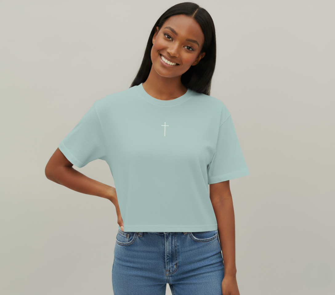 Woman wearing a light blue t-shirt with a white cross on a plain background