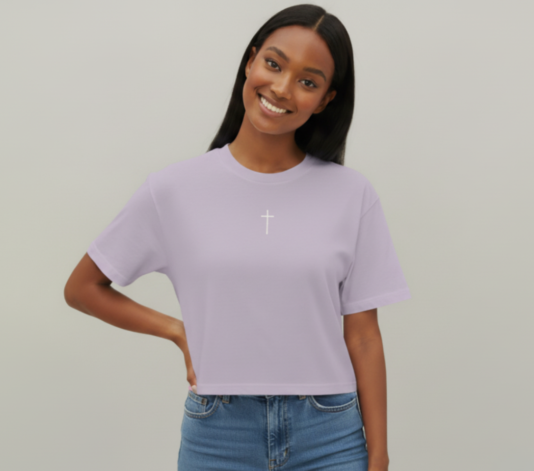 Woman wearing a light purple t-shirt with a white cross design on a plain background